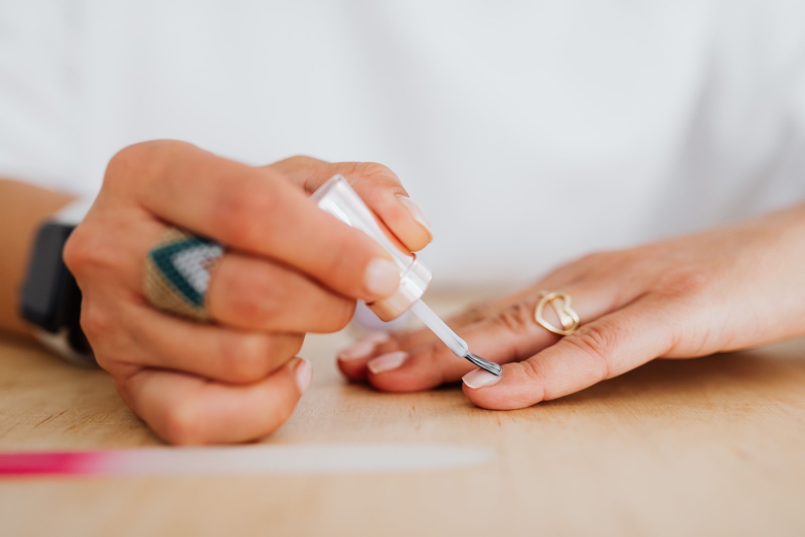 Nude press-on nail being applied to a natural nail bed