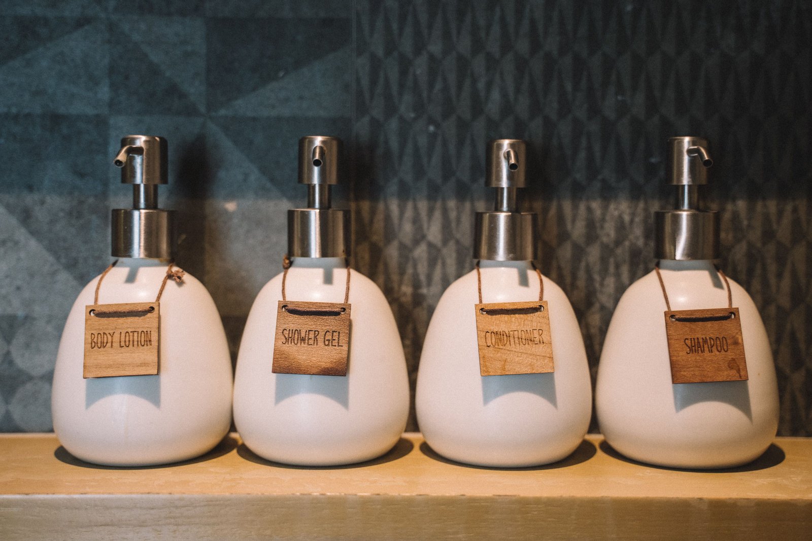 Pump bottles holding shampoo and bath essentials on a wooden shelf
