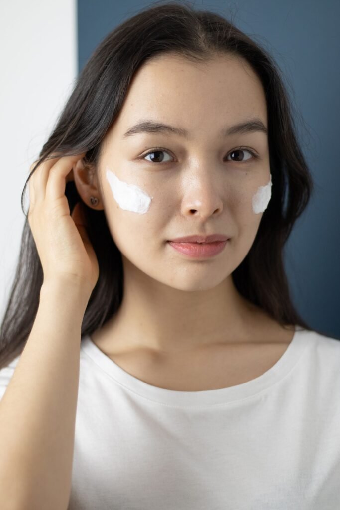 Woman moisturizing her face, the first step before using the best setting spray for dry skin