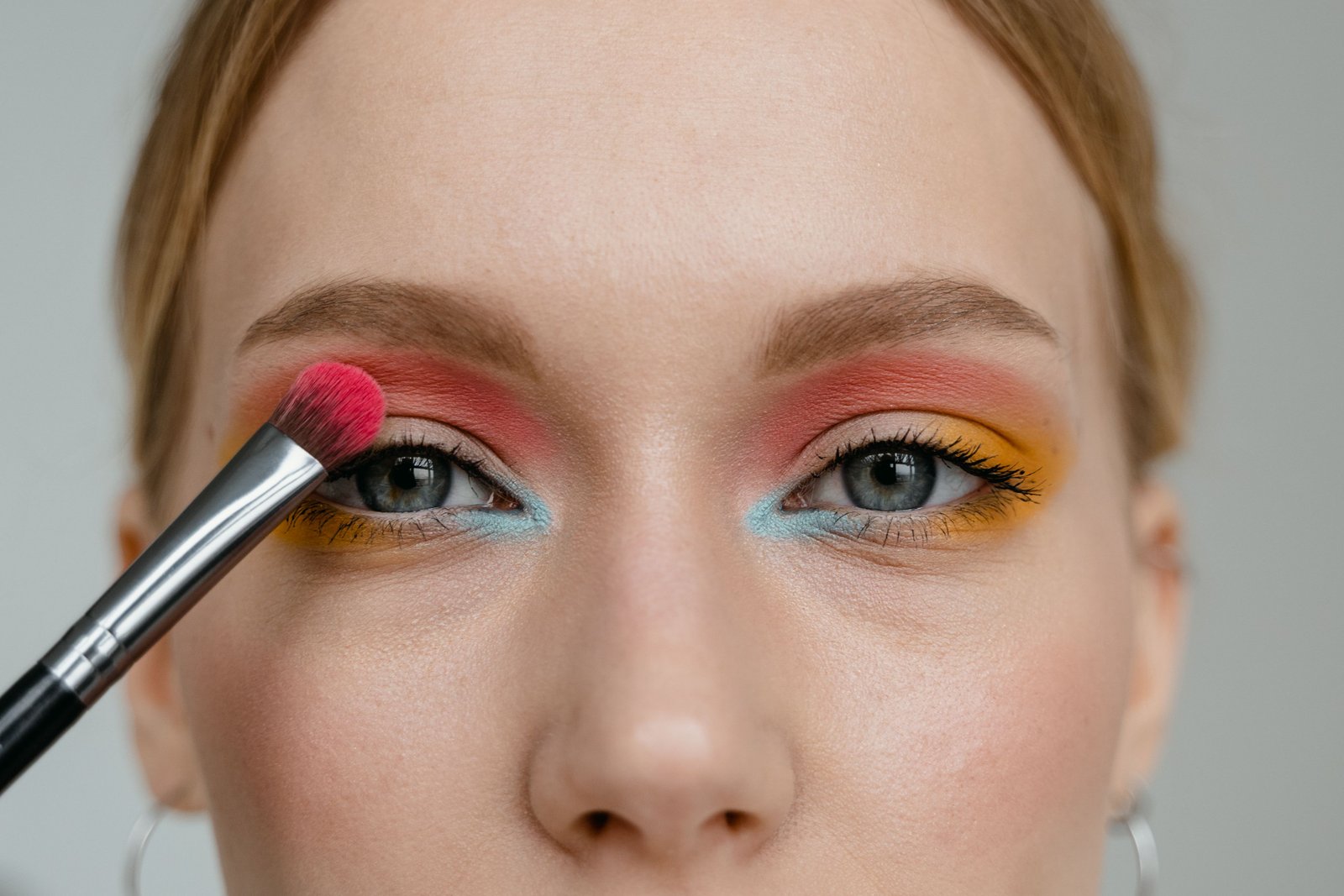 Artist applying vivid color detail as part of a creative face paint look
