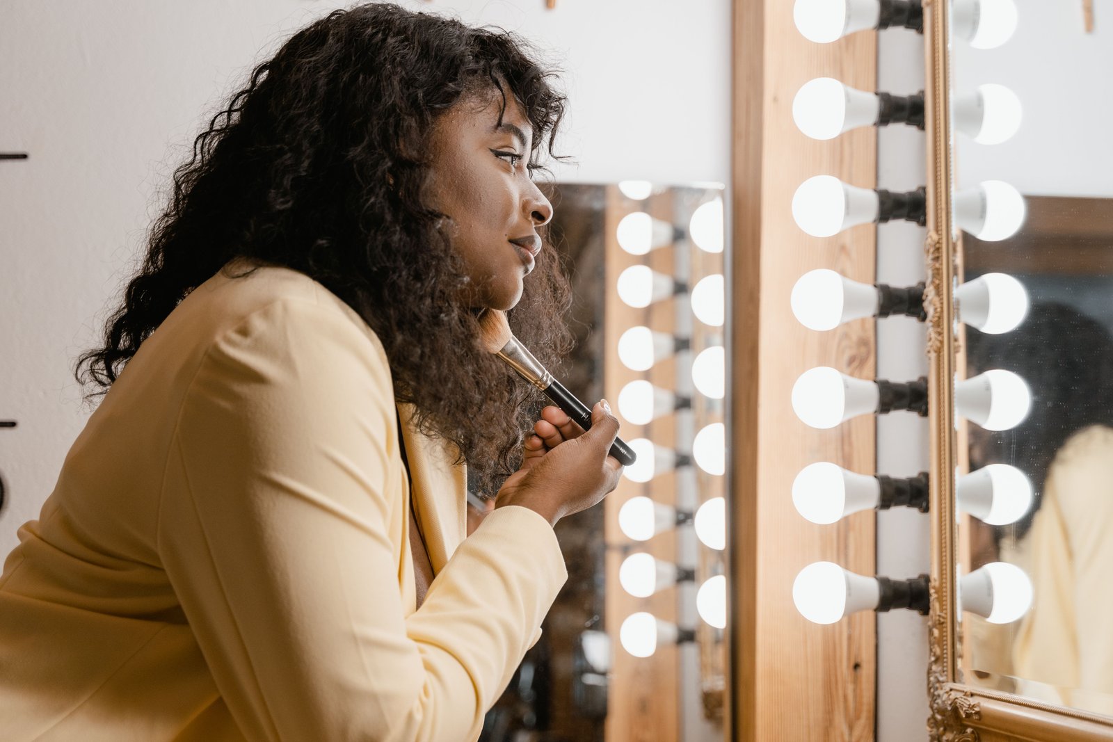 Woman applying makeup in a well-lit vanity area