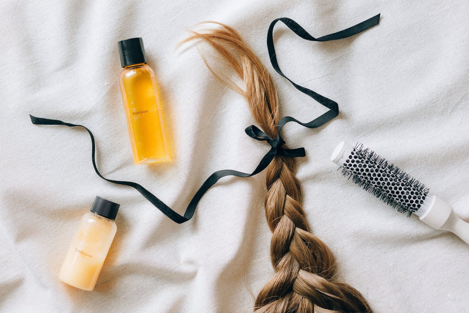 Flat lay of hair oil bottles with braided hair and a brush