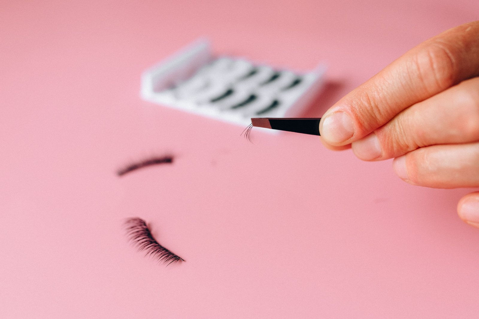 Close-up of applying false eyelash clusters with tweezers