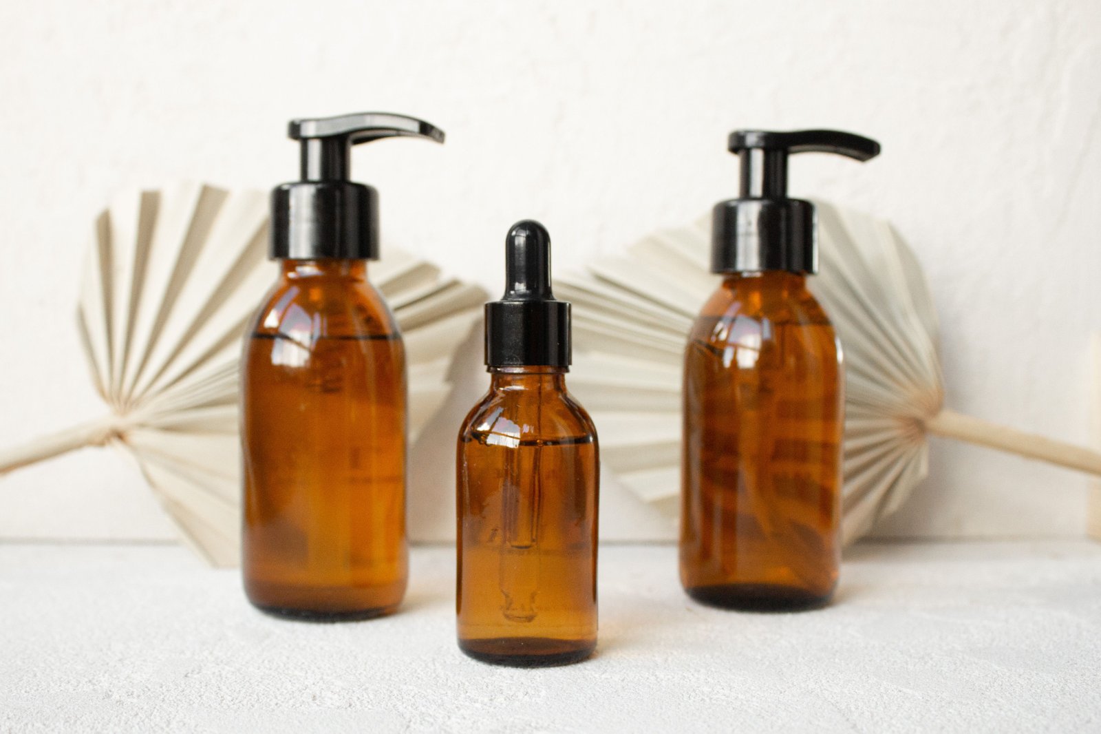 Glass hair serum bottles arranged in a minimalist bathroom setup