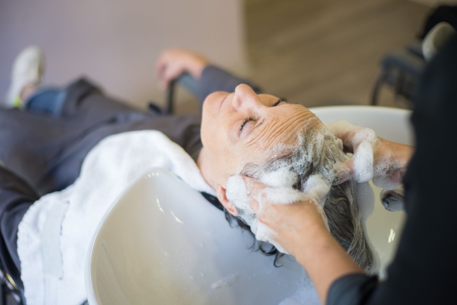 Woman enjoying a relaxing hair wash with shampoo in a salon