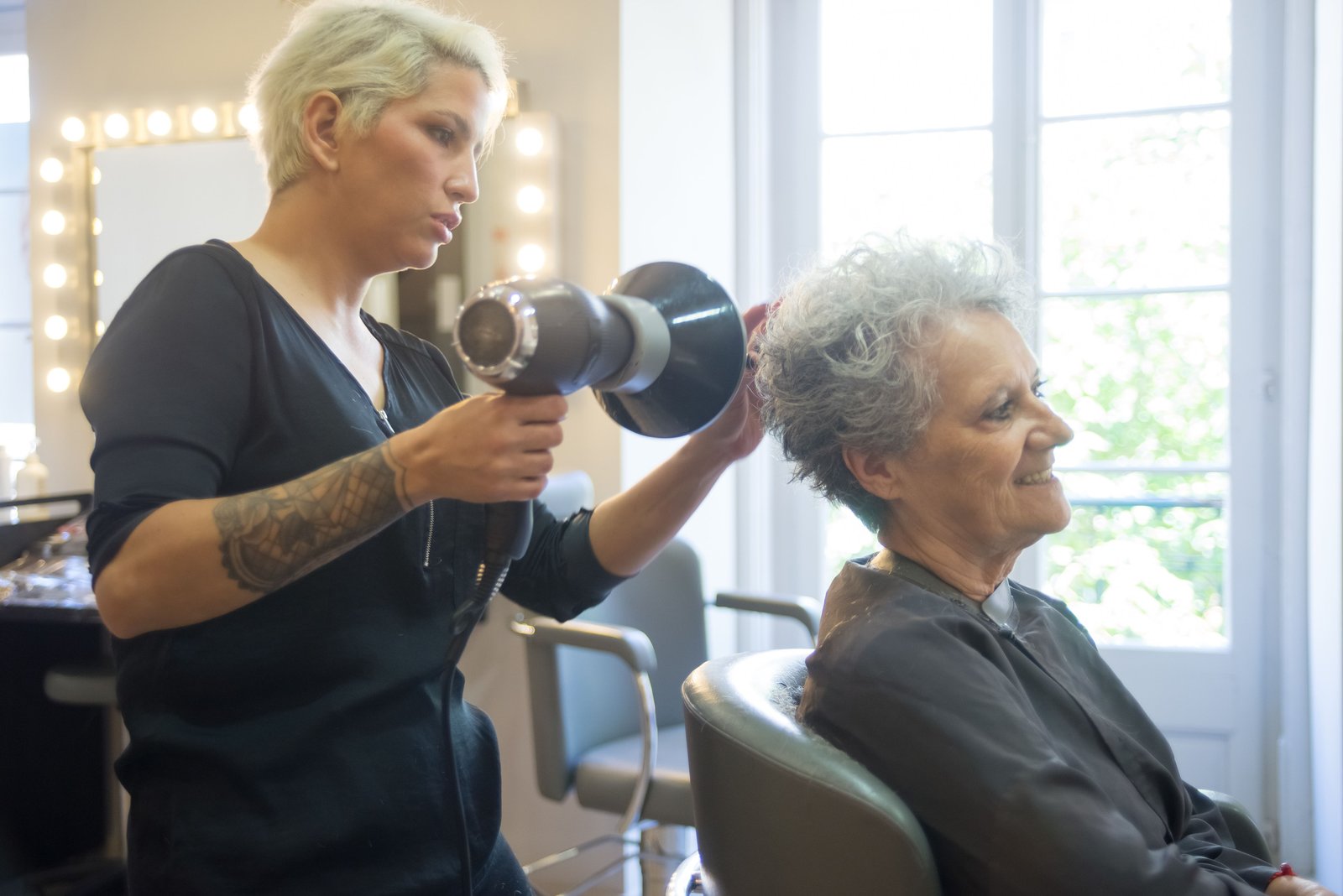 Hair stylist blow drying a client's hair in a modern salon